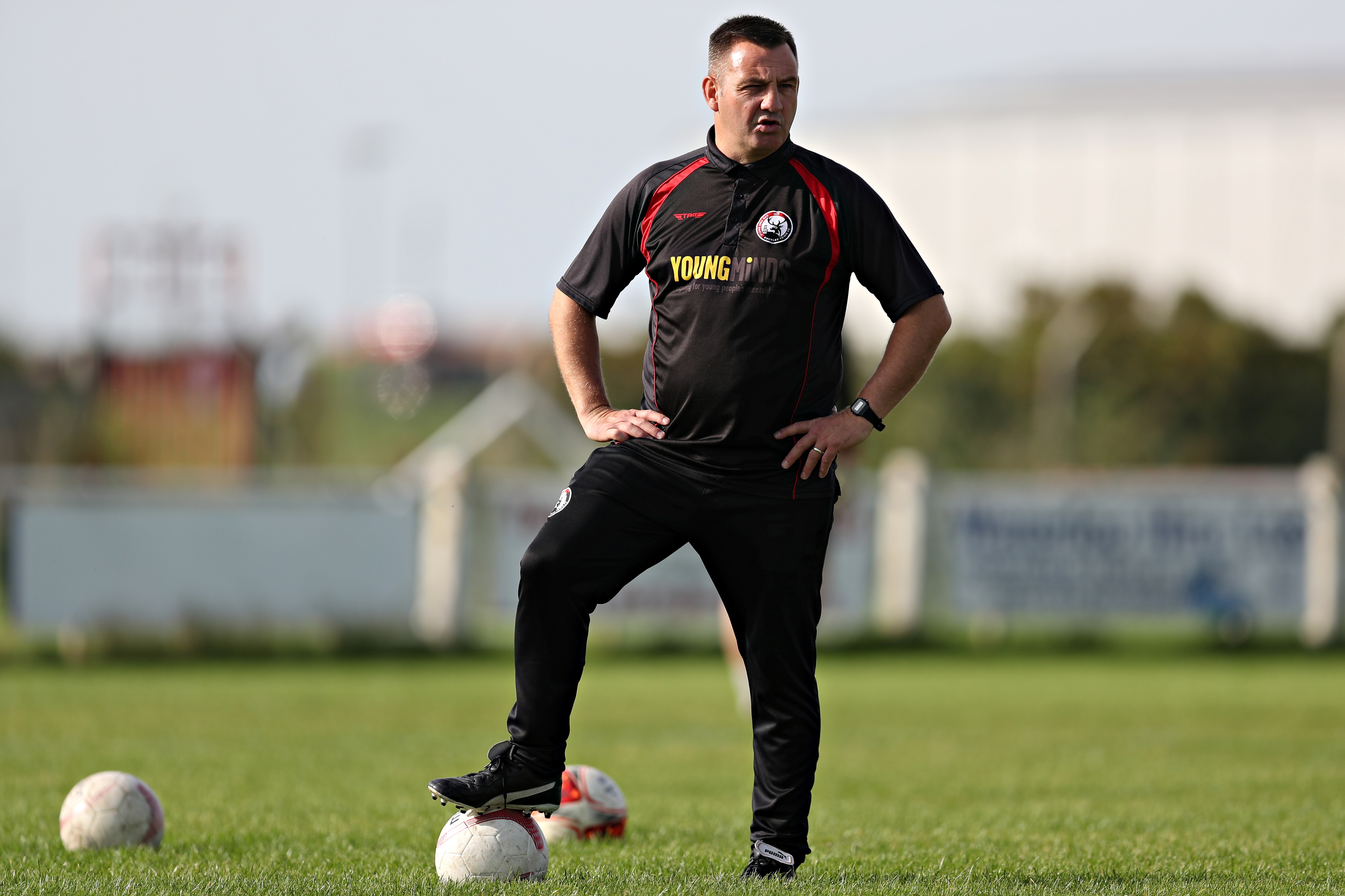 Buckley Town manager Jason Aldcroft looks on with a football underneath his feet.