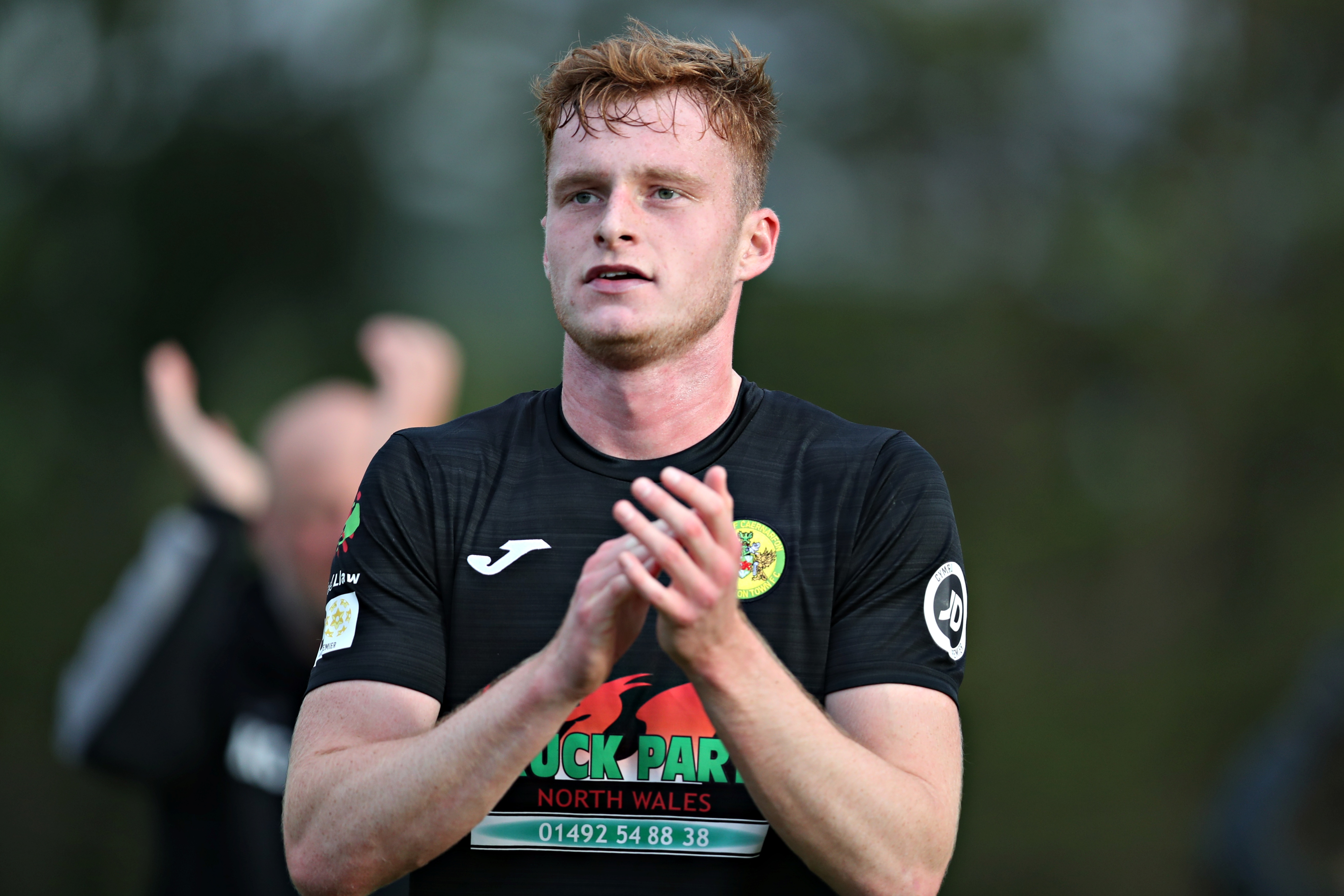 Zack Clarke applauds the Caernarfon Town fans