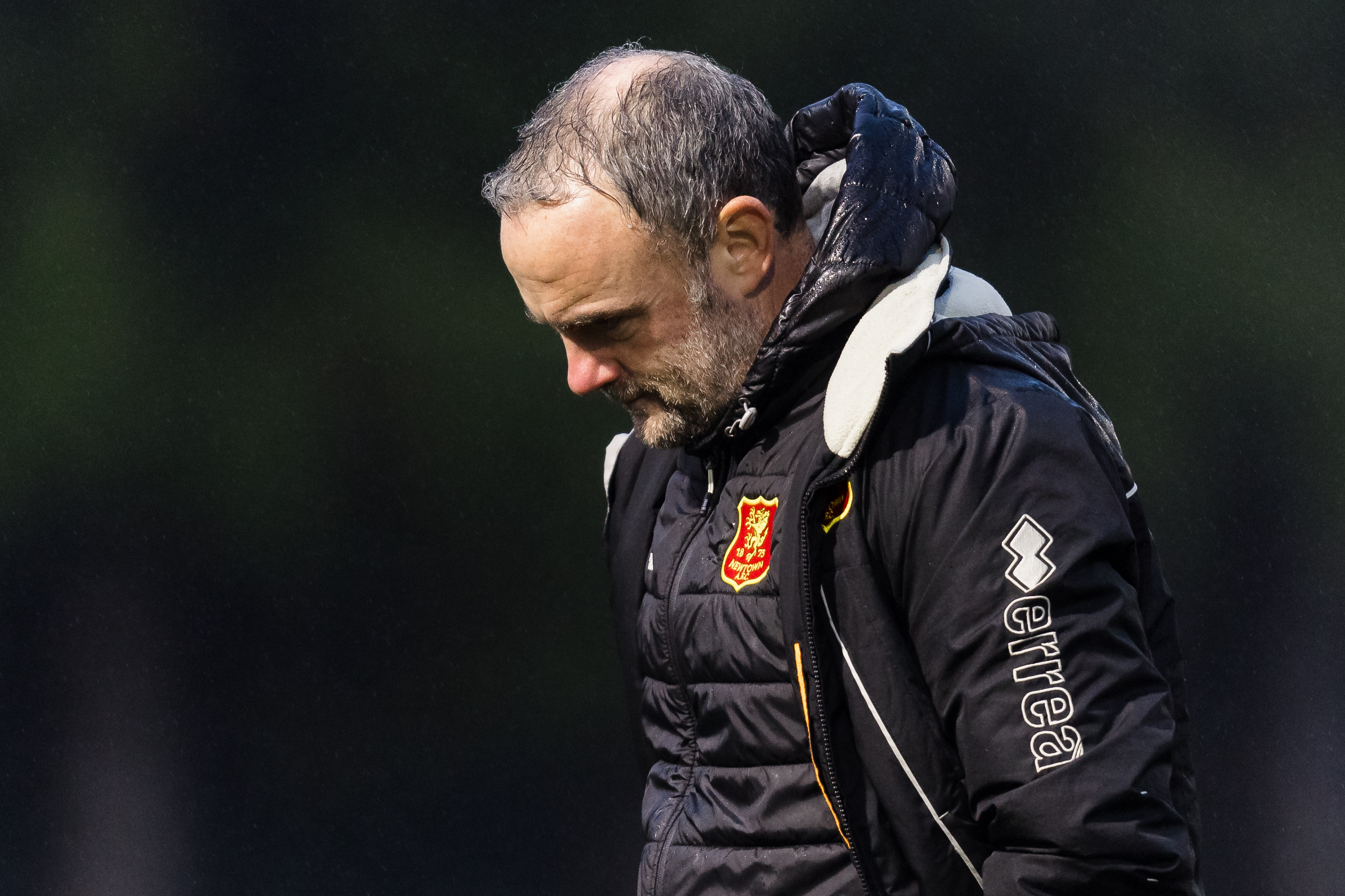 Newtown manager Chris Hughes looks to the ground with a dejected face.