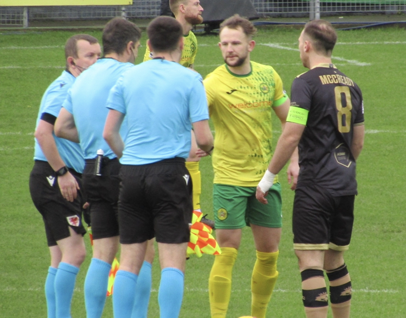 Caernarfon Town and Colwyn Bay captains exchange handshakes with the referee.