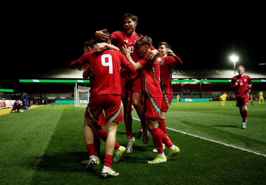 Lewis Koumas is mobbed by his teammates after scoring for Wales against Luthuania