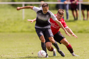 PENRHIWCEIBER, WALES - 27 JULY 2024: Baglan Dragons' Tom Randall and Penrhiwceiber's Jarrad Welch during the 2024/25 JD Cymru South League fixture between Penrhiwceiber Rangers F.C. & Baglan Dragons FC at Glasbrook Field, Rhondda, Wales.