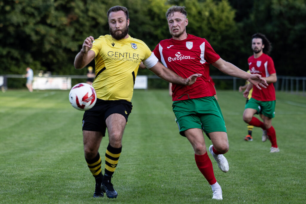 TAFFS WELL, WALES - 19th JULY 2024:
Vaughn Fowler of Taffs Well in action against Isaac Richards of Merthyr Town.
Taffs Well v Merthyr Town in the Nathaniel MG Cup at Rhiw Dda’r on the 19th July 2024. (Pic by Lewis Mitchell/FAW)