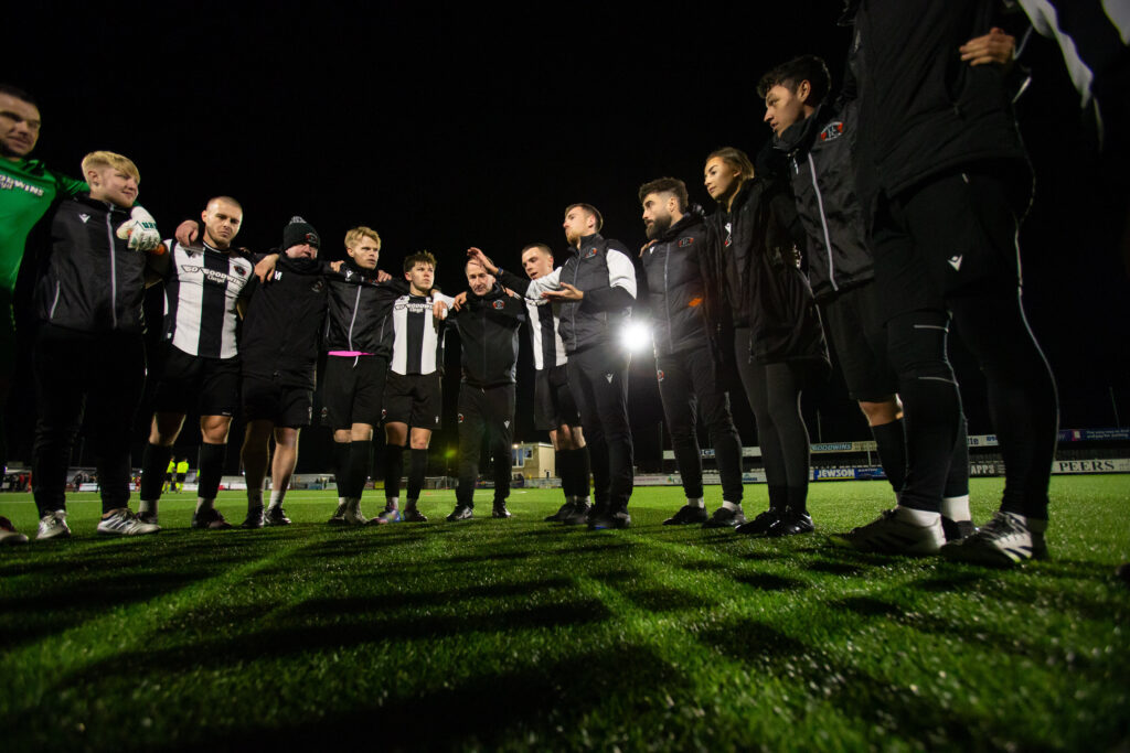 Llandudno Manager, Jordan Hadaway talks to his players following the JD Welsh Cup fixture between Llandudno and Connah’s Quay Nomads at the Go Goodwins Stadium, Llandudno. 18th of November, Llandudno, Wales