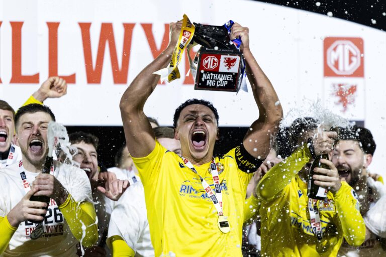 BRIDGEND, WALES - 28 FEBRUARY 2026: Barry Town's Callum Sainty lifts the trophy during the 2025/26 Nathaniel MG Cup Final fixture between The New Saints FC & Barry Town United AFC at the Dragonbet Stadium, Bridgend, Wales