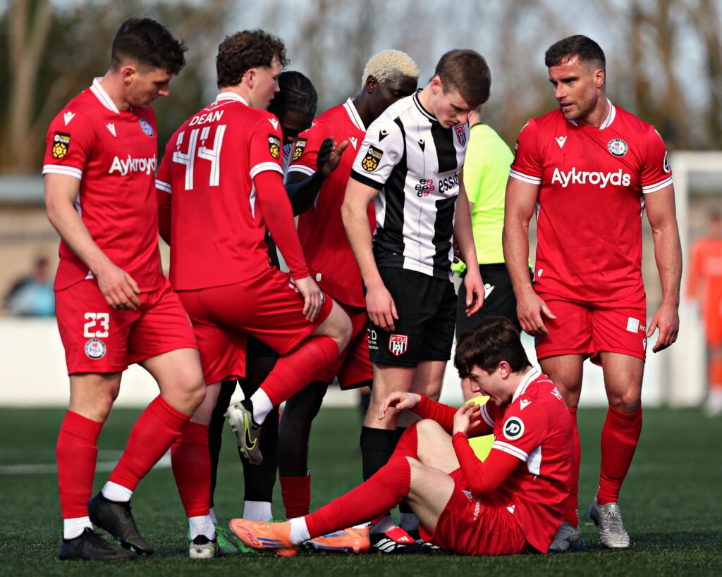 Ben Wynne of Flint Town United stands over Liam Higgins of Bala Town during Flint Town United vs Bala Town 