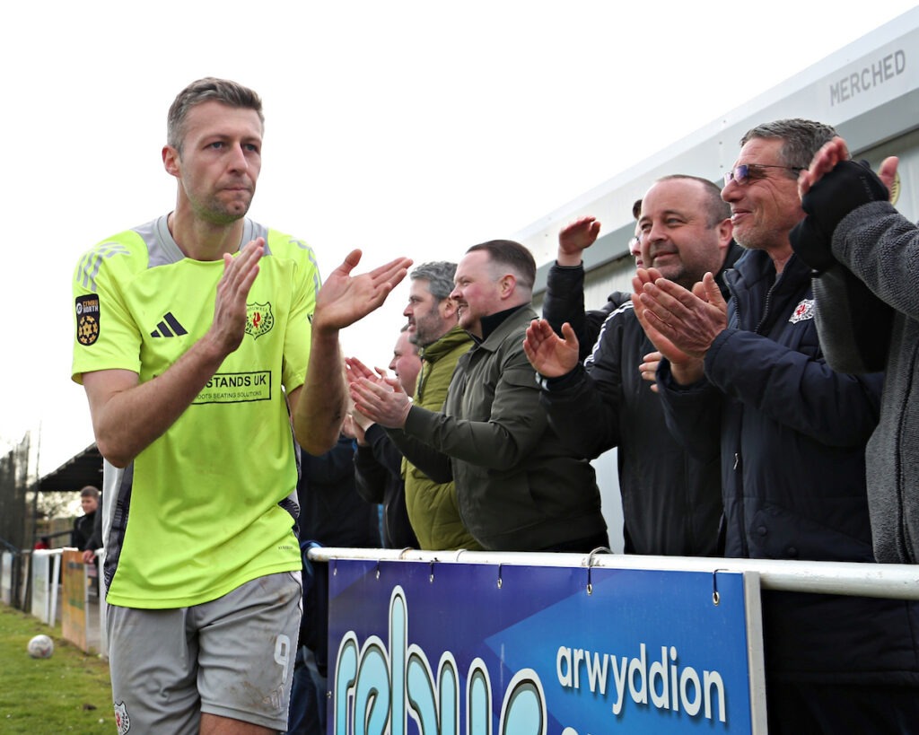 Craig Lindfield of Holywell Town celebrates at the full-time whistle with supporters after a JD Cymru North match against Penrhyncoch at Cae Baker.