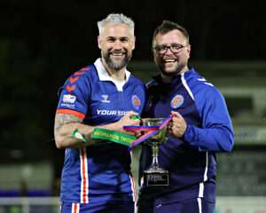 Jamie Reed of CPD Dinas Bangor 1876 and Michael Johnston, Manager of CPD Dinas Bangor 1876 celebrates lifting the Lock Stock Ardal North West after CPD Dinas Bangor 1876 vs Penmaenmawr Phoenix in Round 26 at Bangor City Stadium, Bangor