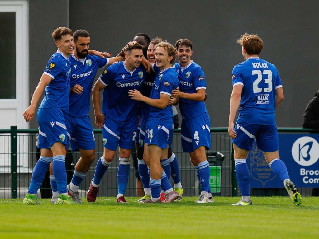 Danny Davies of The New Saints celebrates with his team mates after scoring a goal to make it 2-3 during the Novira Cymru Premier game between Caernarfon Town and The New Saints at the The Oval Stadium in Caernarfon