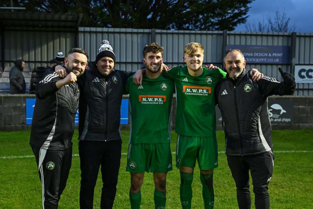 Paul Moore, Manager of Rhyl 1879 celebrates with his assistants and the goal scorers Ben Lightfoot and Jack Parry at the end of the JD Welsh Cup between Porthmadog and Rhyl 1879 at the Y Traeth Stadium in Porthmadog
