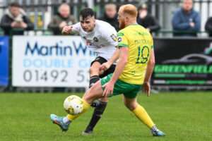 Ben Lawrence of Rhyl 1879 passes the ball during the JD Welsh Cup Semi-Final between Rhyl 1879 and Caernarfon Town at The Blue Turtle Arena in Colwyn Bay