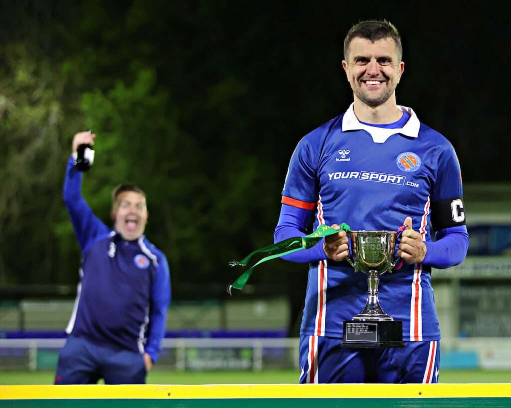 Tom Clarke of CPD Dinas Bangor 1876 celebrates lifting the Lock Stock Ardal North West after CPD Dinas Bangor 1876 vs Penmaenmawr Phoenix in Round 26 at Bangor City Stadium, Bangor
