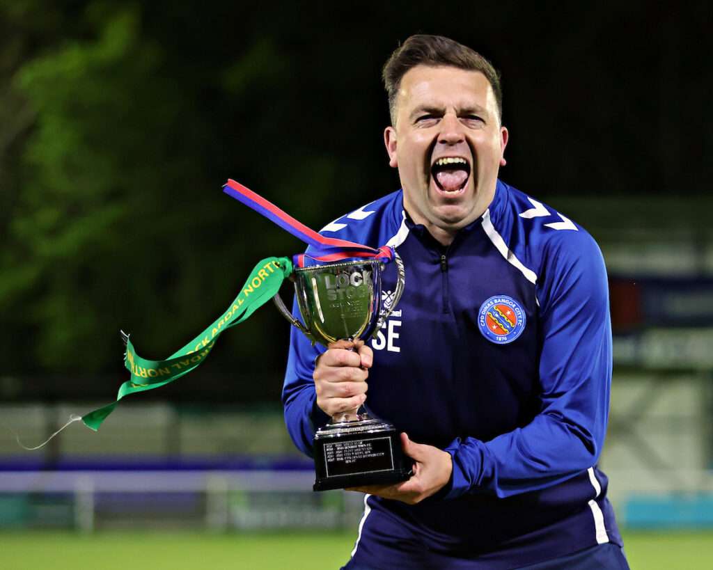 Sean Eardley, Assistant Manager of CPD Dinas Bangor 1876celebrates lifting the Lock Stock Ardal North West after CPD Dinas Bangor 1876 vs Penmaenmawr Phoenix in Round 26 at Bangor City Stadium, Bangor