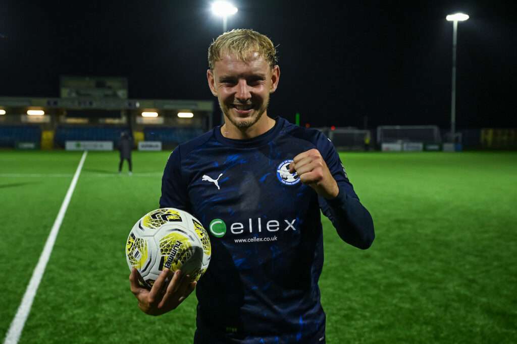 BROUGHTON, WALES - 18 SEPTEMBER 2026: George Peers of Airbus UK Broughton celebrates at the end of the game with the match ball after scoring a hat-trick during the Novira Cymru Premier game between Airbus UK Broughton and Flint Town United at The Hollingsworth Group Stadium in Broughton. (Pic by Craig Thomas/FAW)