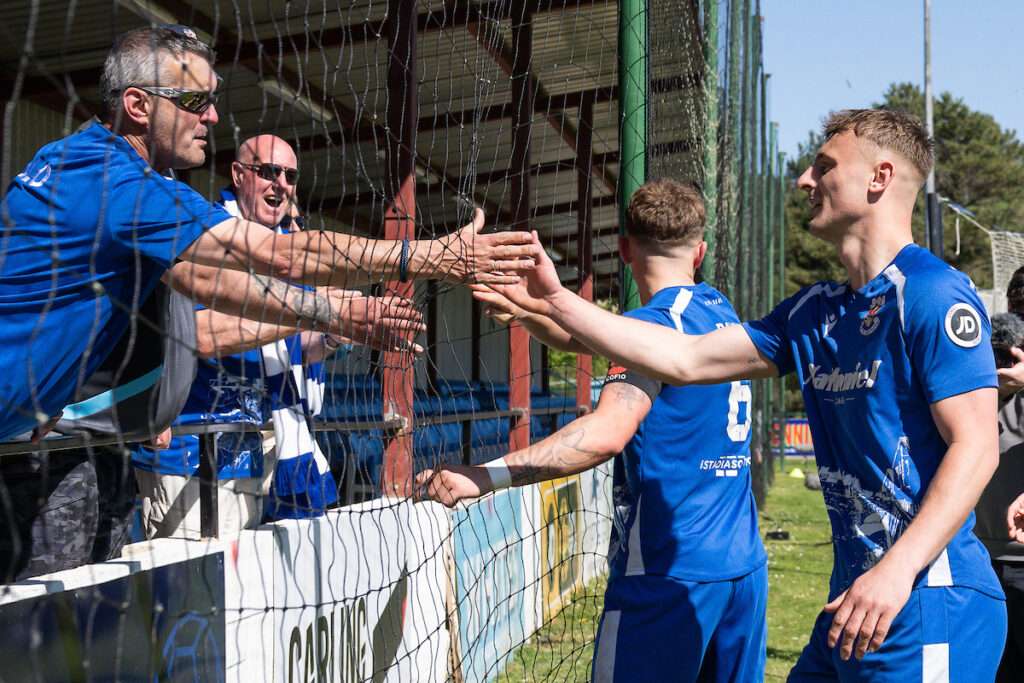 Noah Daley of Penybont celebrates with fans at the end of the JD Cymru Premier European Play off Semi Final between Colwyn Bay and Penybont FC at The Blue Turtle Arena in Colwyn Bay.
