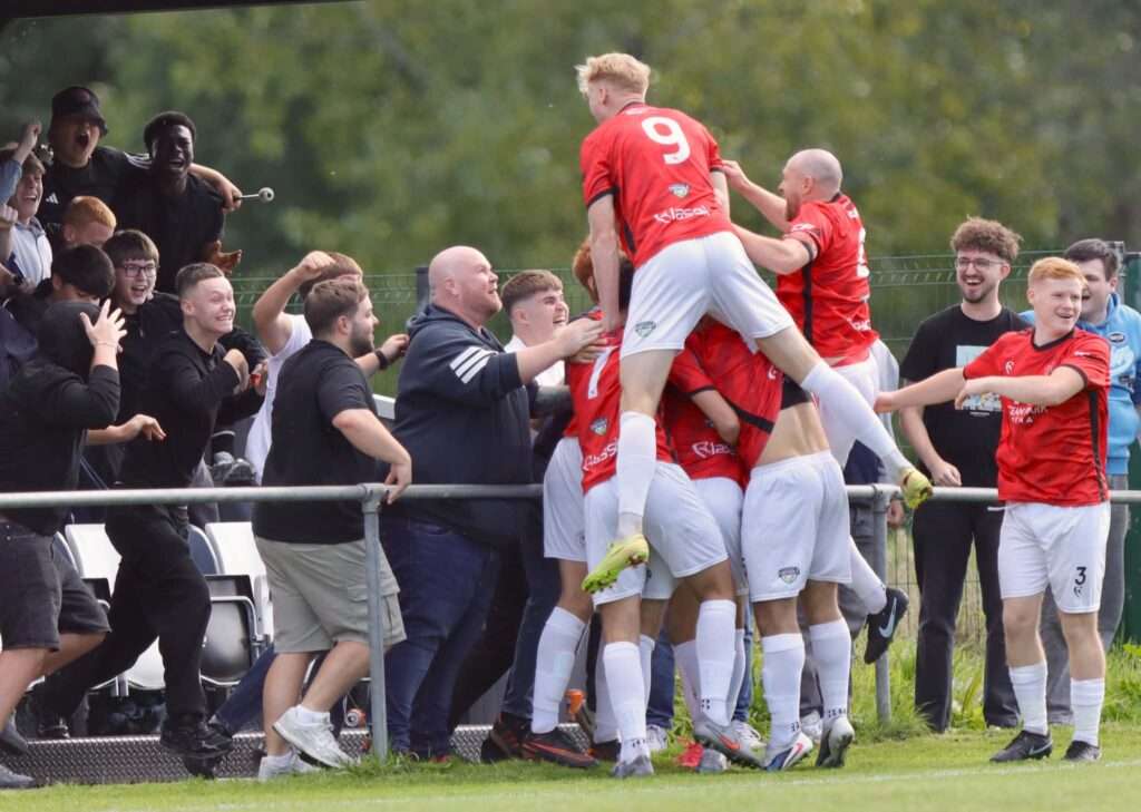 Caerau Ely players celebrate with fans as Lewis Harling scores against Cardiff Dracs in the Cymru South