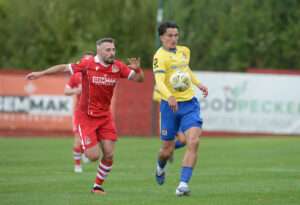 Barry Town United’s Owen Brain battles with Briton Ferry Llansawel’s Tom Price during the Novira Cymru Premier match at the Renewable Centre Stadium.
