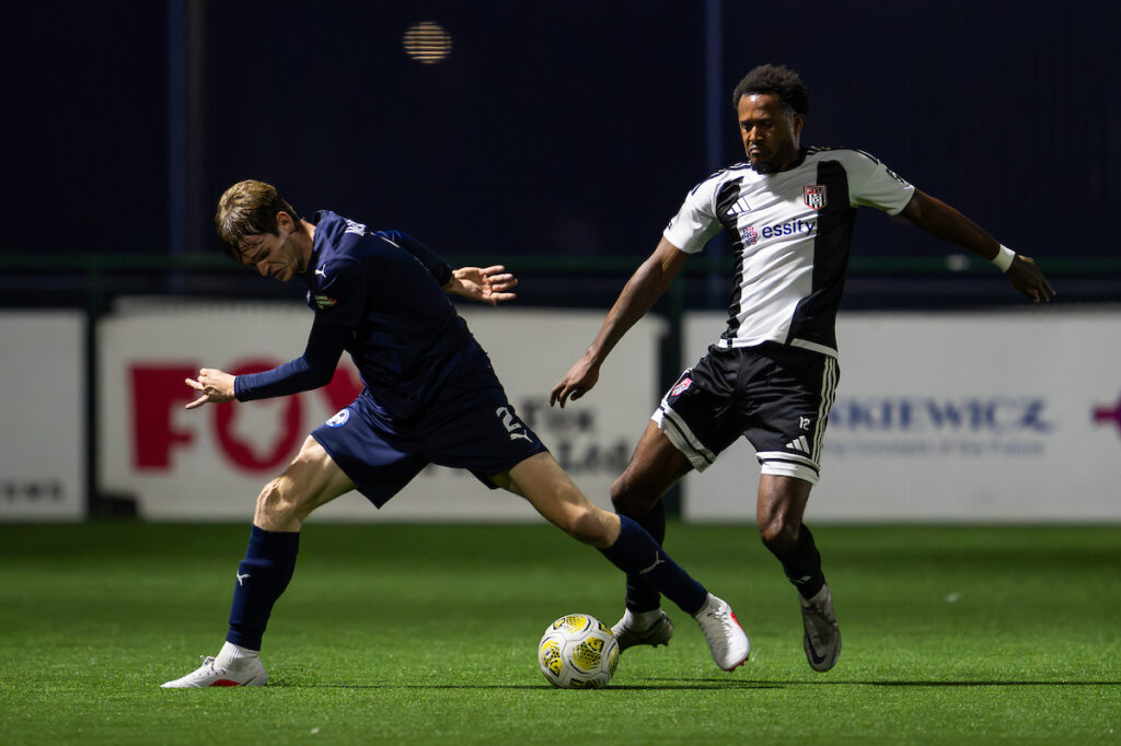 Tyler McManus of Airbus UK Broughton and  Flint Town's Akeel Francis battles for the ball during the Novira Cymru Premier game between Airbus UK Broughton 