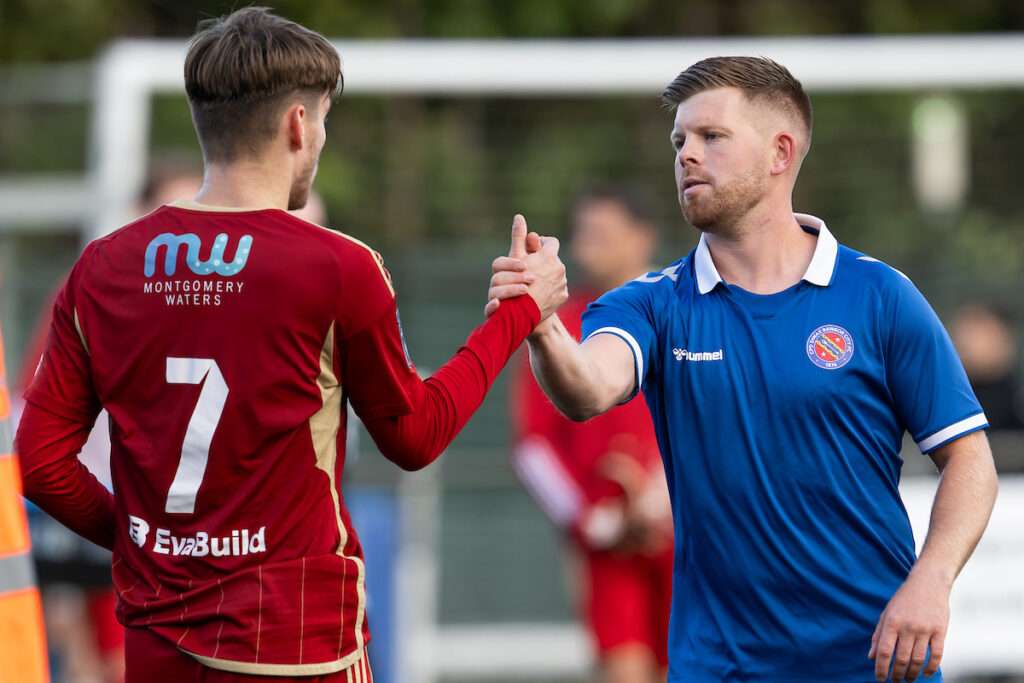 players shake hands at the end of the Novira Cymru Leagues North game between Newtown and CPD Dinas Bangor 1876 at Latham Park in Newtown