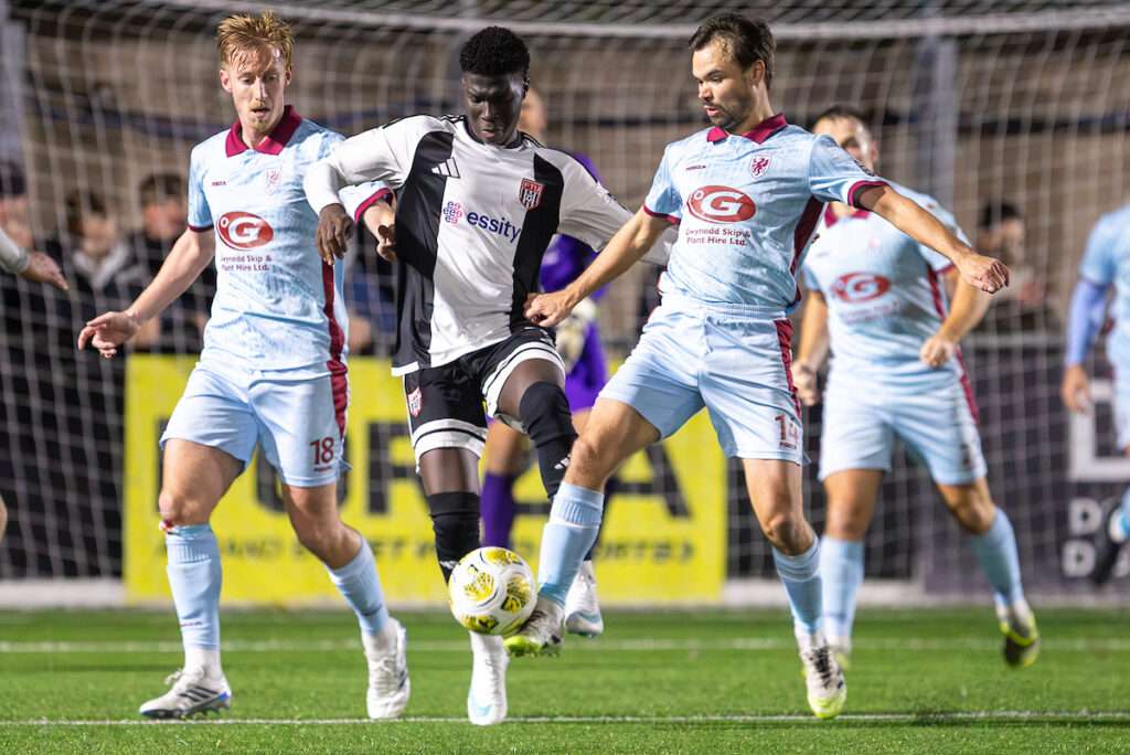 Isaac Modi of Flint Town United and Noah Edwards of Caernarfon Town battle for the ball during the FAW Welsh Cup match between Flint Town United and Caernarfon Town at Essity Stadium,