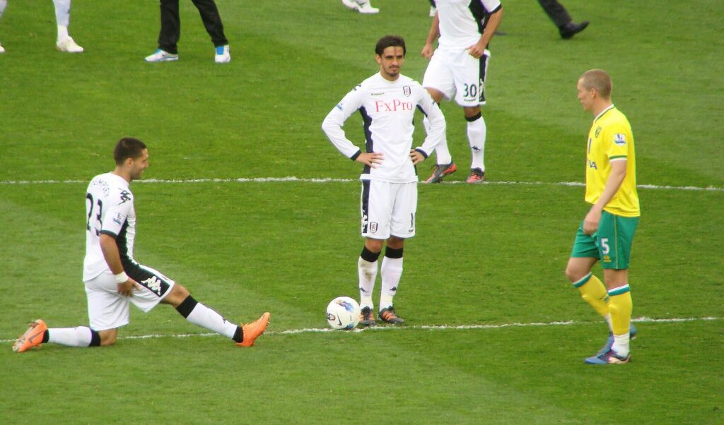 Clint Dempsey (left) stretches while Bryan Ruiz (center) stands at the center circle. Steve Morison to the right.
