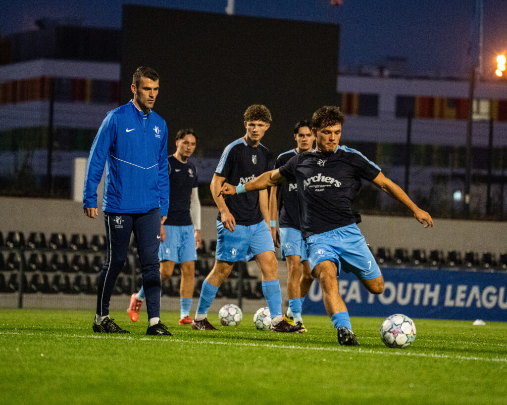 Adam Roscrow watches on as Mitch Ford strikes a ball before kick-off against UNA Strassen (Image Credit: Samuel Jones)